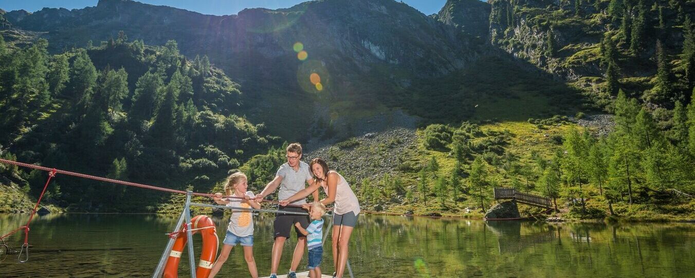 Familie fährt mit einem Floß über den Untersee in Schladming, umgeben von ruhigem Wasser und Natur. © Gerhard Pilz