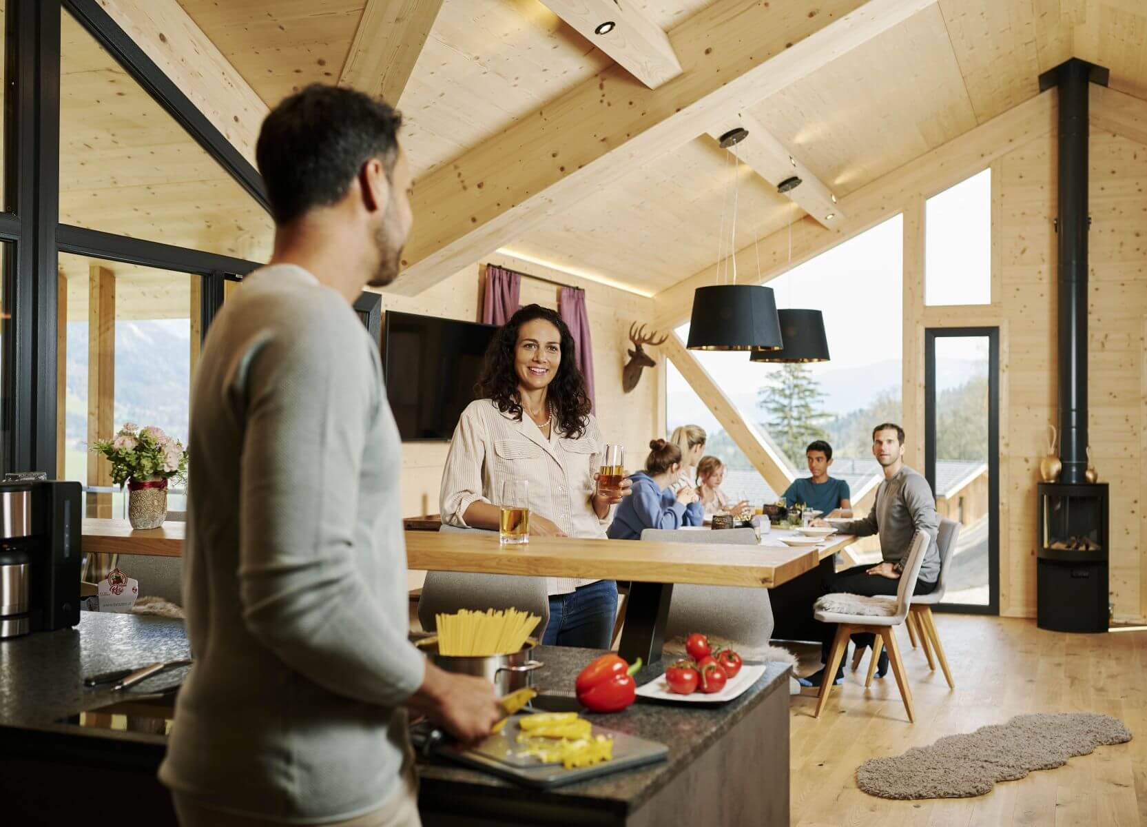 Familie kocht im Ferienhaus, Kinder spielen am Esstisch