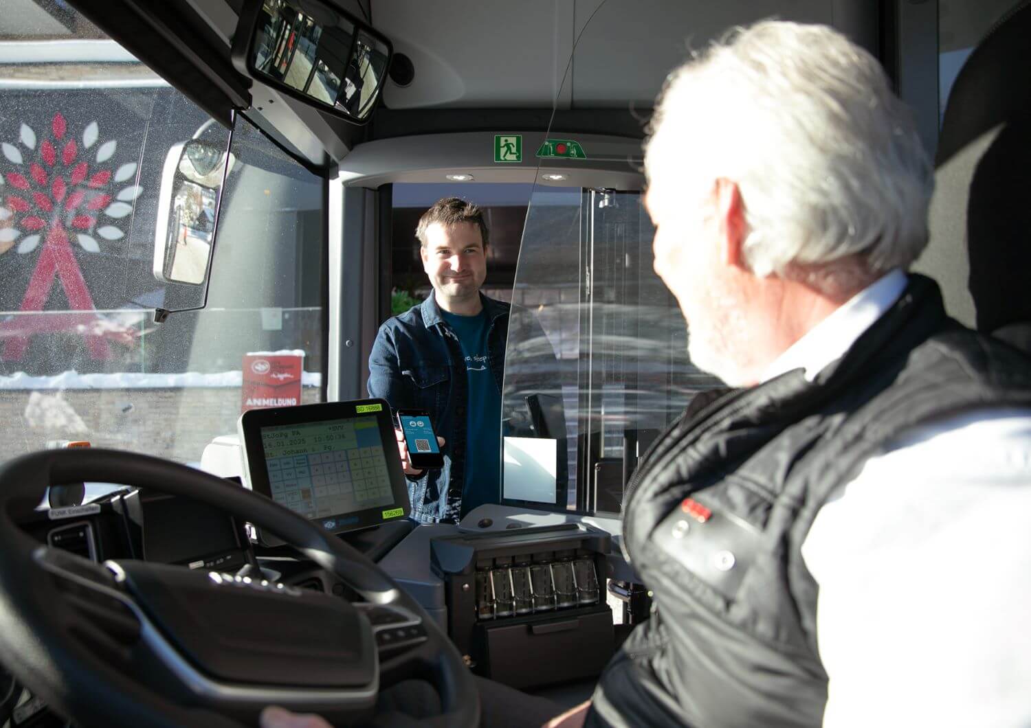 A man greets the bus driver when boarding the bus and shows his Guest Mobility Ticket.