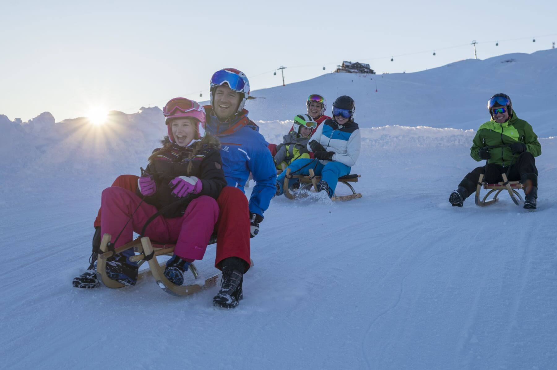 Friends with children and 4 sledges on a toboggan run